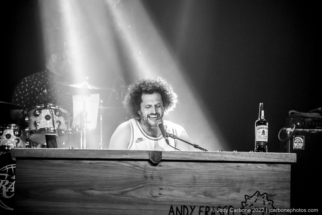 Black and white concert photography - Andy Frasco playing piano and singing under beams of white light