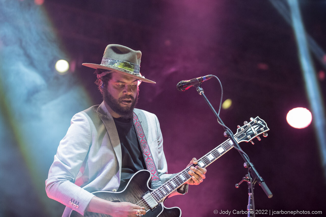 Gary Clark Jr. with beams of light in front of a magenta background