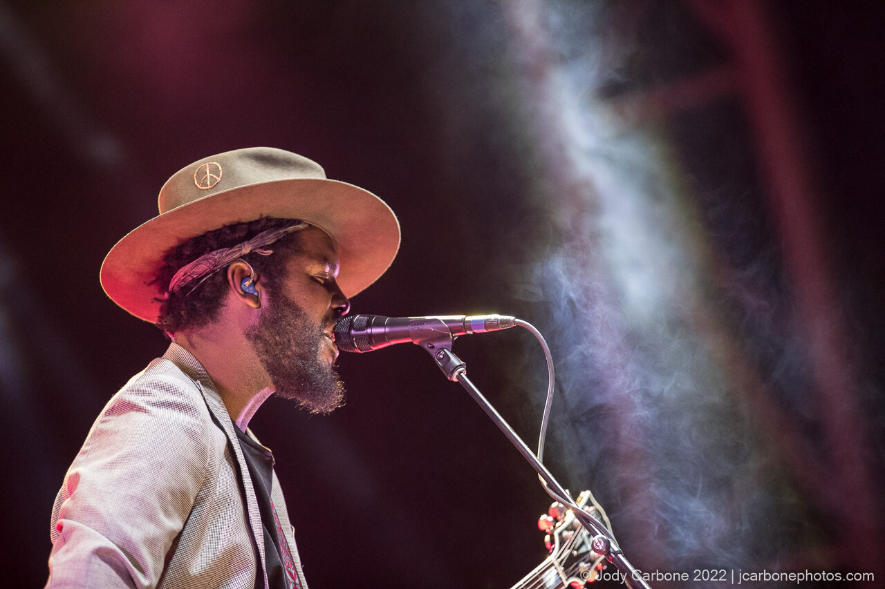 Gary Clark Jr. sings into microphone with cloud of haze in front of him