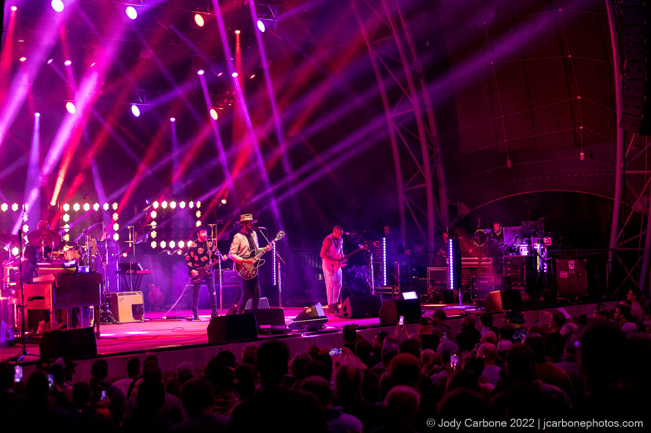Gary Clark Jr. and band on stage under magenta and purple beams of light